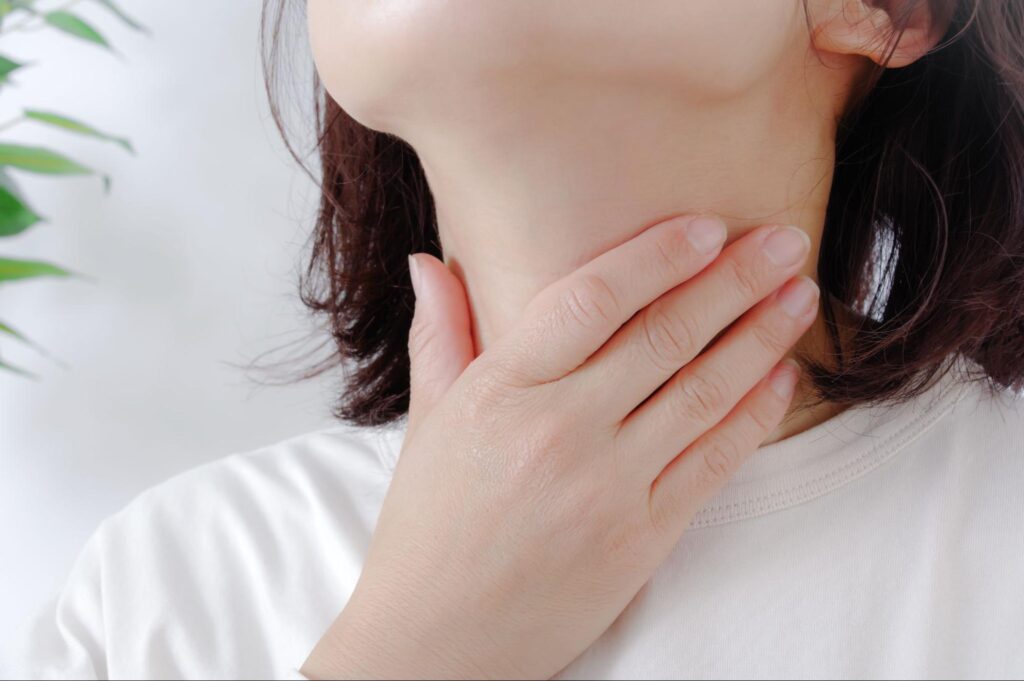 喉を押さえる女性