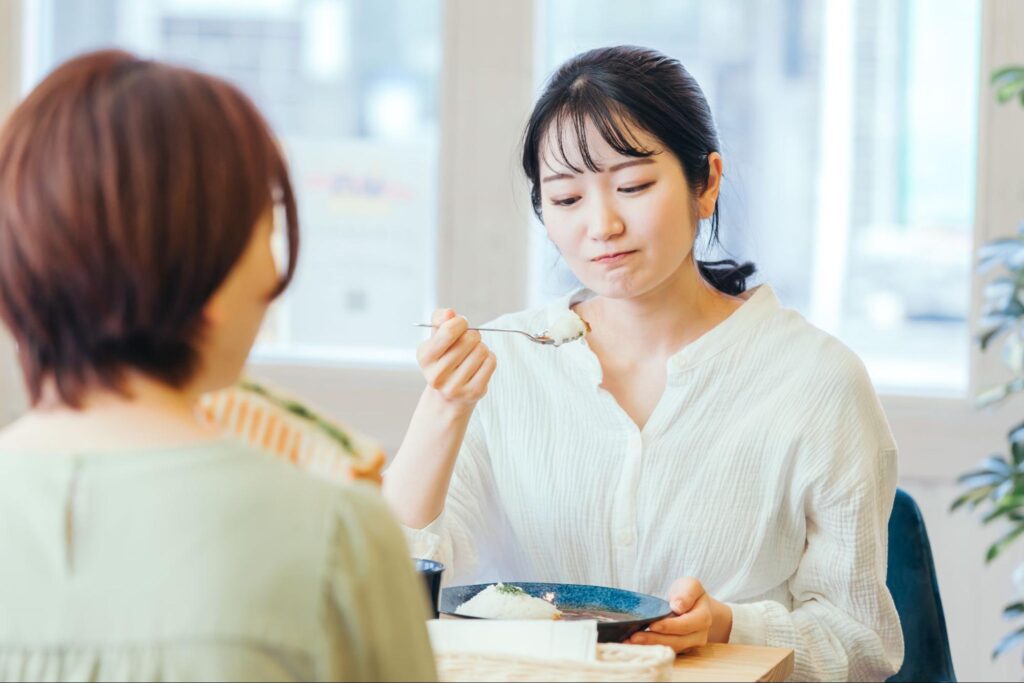 親知らず抜歯後の食事にカレーを選んでしまい、しみるのか浮かない顔をする女性