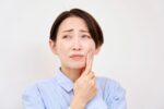 親知らずが痛み頬を押さえる女性