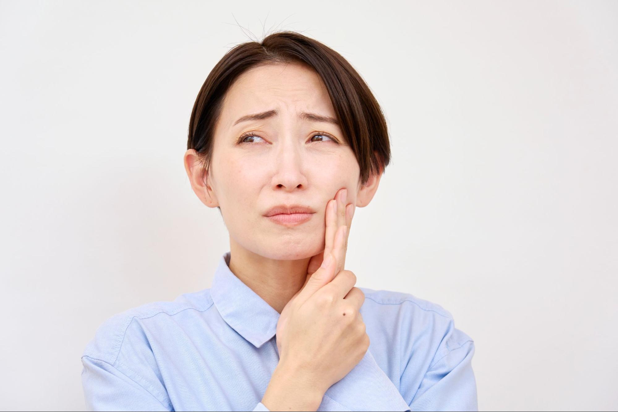 親知らずが痛み頬を押さえる女性