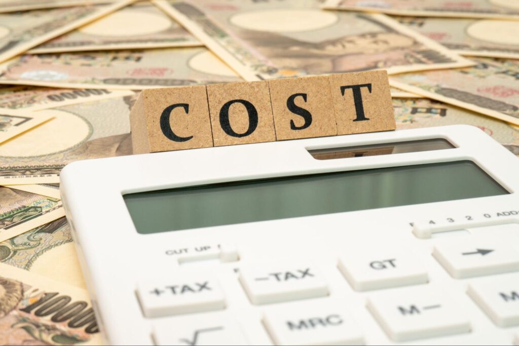 COSTと書かれた木製ブロックと計算機と1万円札