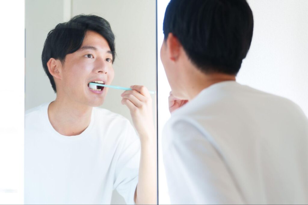 鏡を見ながら歯磨きする男性