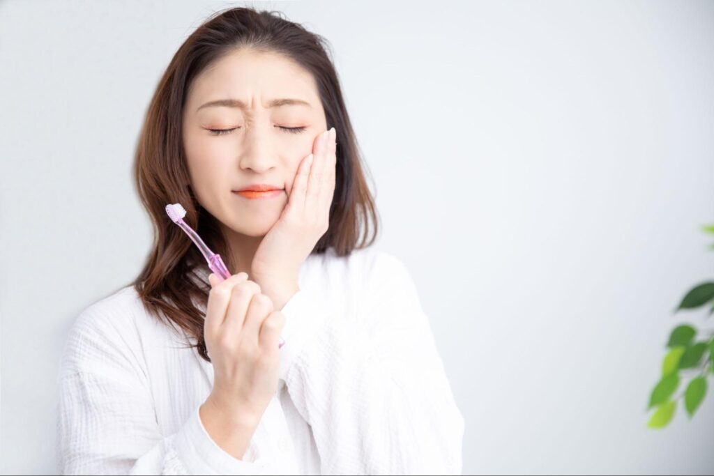 虫歯で歯が痛み頬を押さえる女性