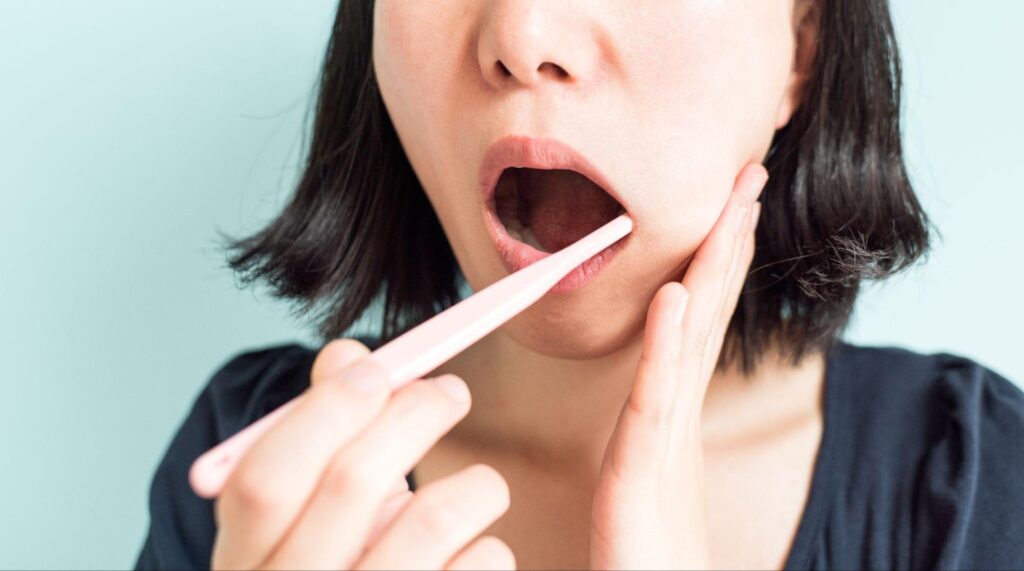 歯磨き中に違和感を感じて頬を押さえる女性