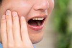 親知らずの痛みで頬を押さえる男性