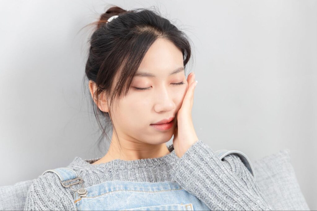 親知らずの痛みで頬を押さえる女性