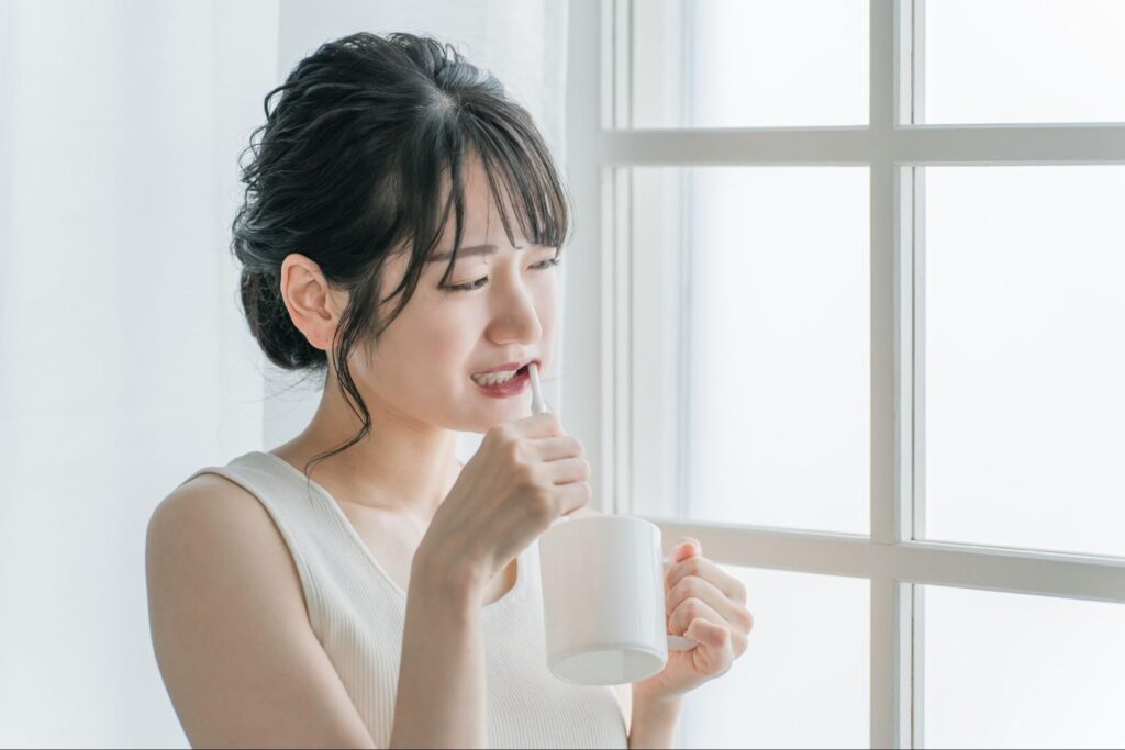 親知らず抜歯後の歯磨きで痛みが走り顔をしかめる女性
