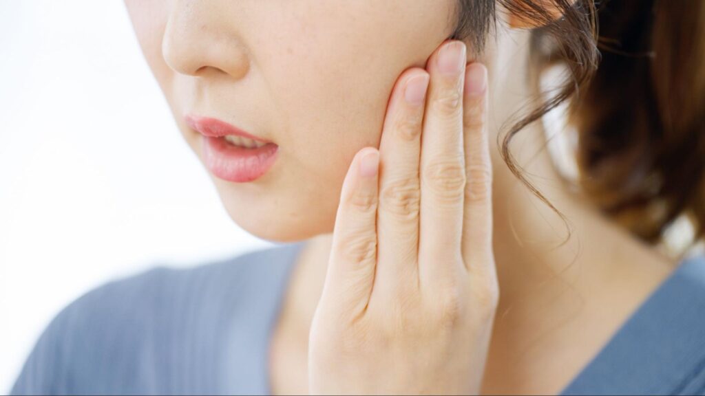 親知らずの痛みで頬を押さえる女性