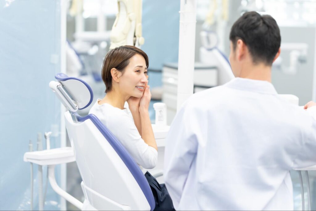 歯科医師に親知らずの痛みについて説明する女性