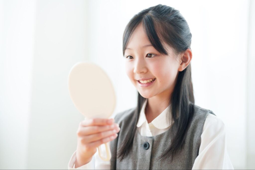 笑顔で鏡を見る中学生