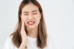 治療後の虫歯が痛くて頬を押さえる女性