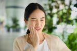 虫歯で歯茎が腫れて痛みがあり頬を押さえる女性