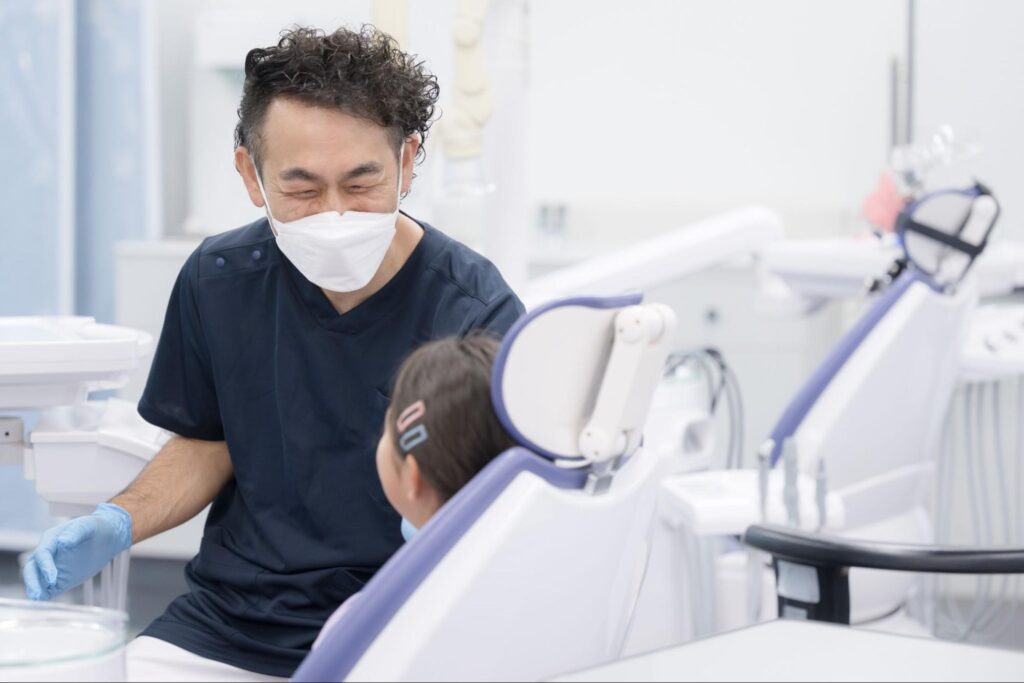 歯科医院の椅子に座って歯科医師と話している子ども