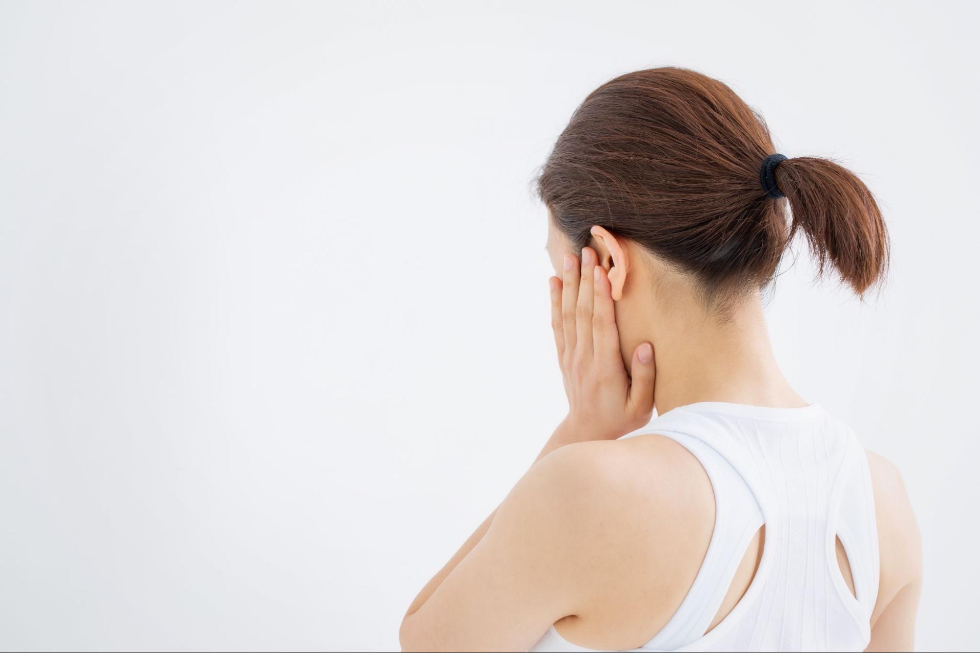 親知らずに痛みを感じて頬を押さえる女性