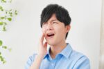 虫歯が痛み頬を押さえる男性