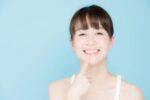 歯を指さして笑顔の女性