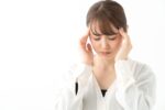 親知らずによる頭痛でこめかみを押さえる女性