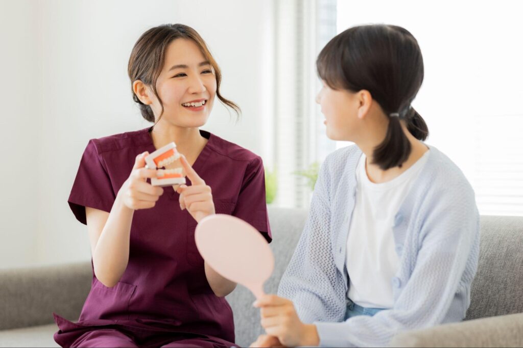歯の模型を使って女子中学生に説明している女性医師