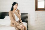 親知らずが生えかけで痛みがあり顎を押さえる女性