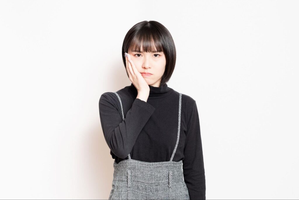 親知らずの痛みで頬を押さえる女性