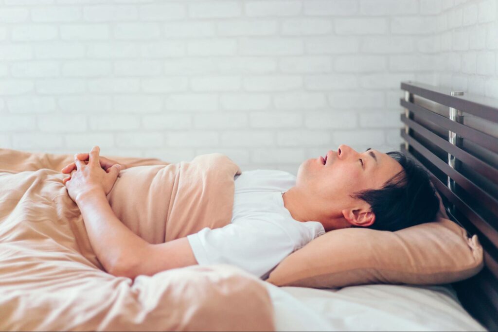 口を開けていびきをかいている睡眠時無呼吸症候の男性