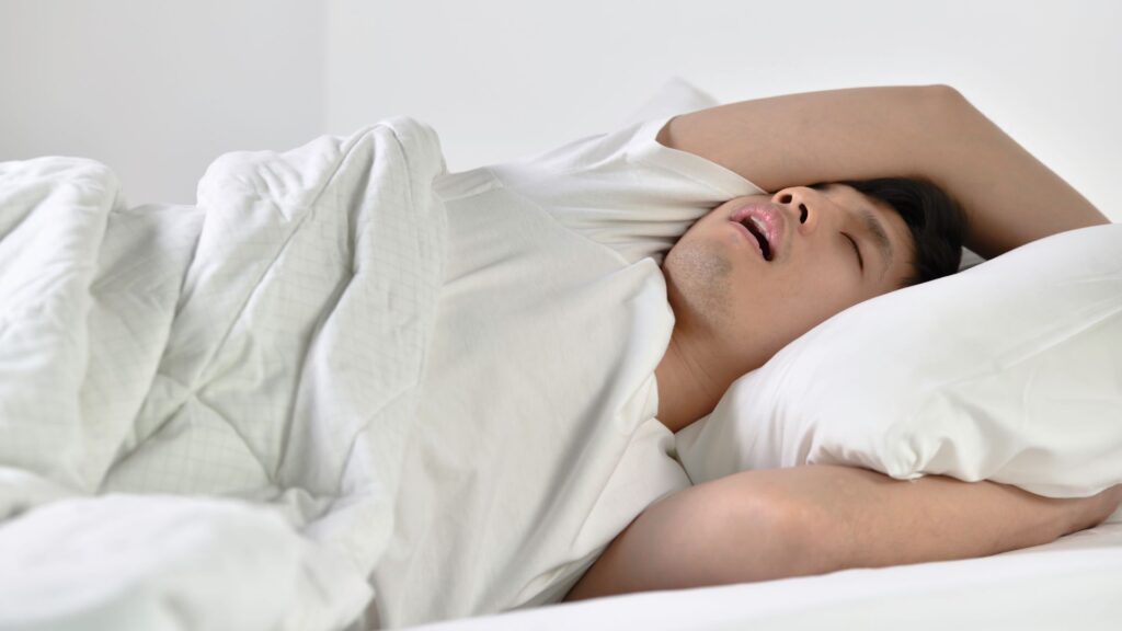 口を開けていびきをかいて寝ている睡眠時無呼吸症候群の男性