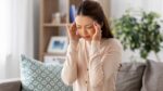 睡眠時無呼吸症候群による頭痛でつらそうにこめかみを押さえる女性