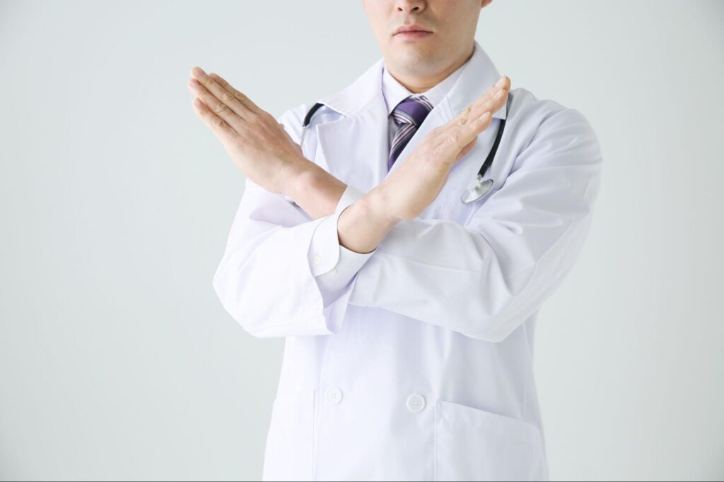 両手でバツマークをつくる男性医師
