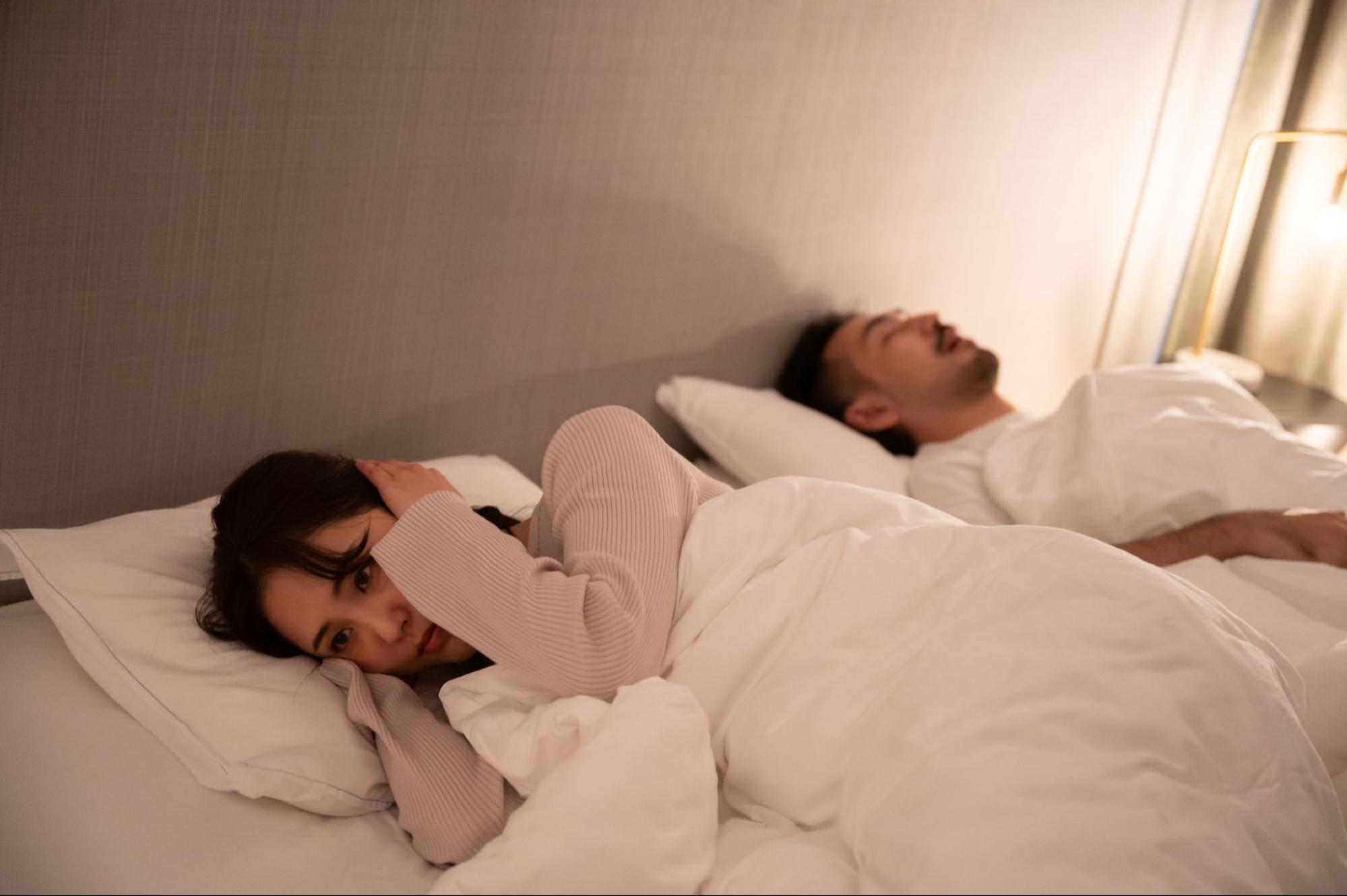 睡眠時無呼吸症候群の夫のいびきに耳を塞ぐ妻