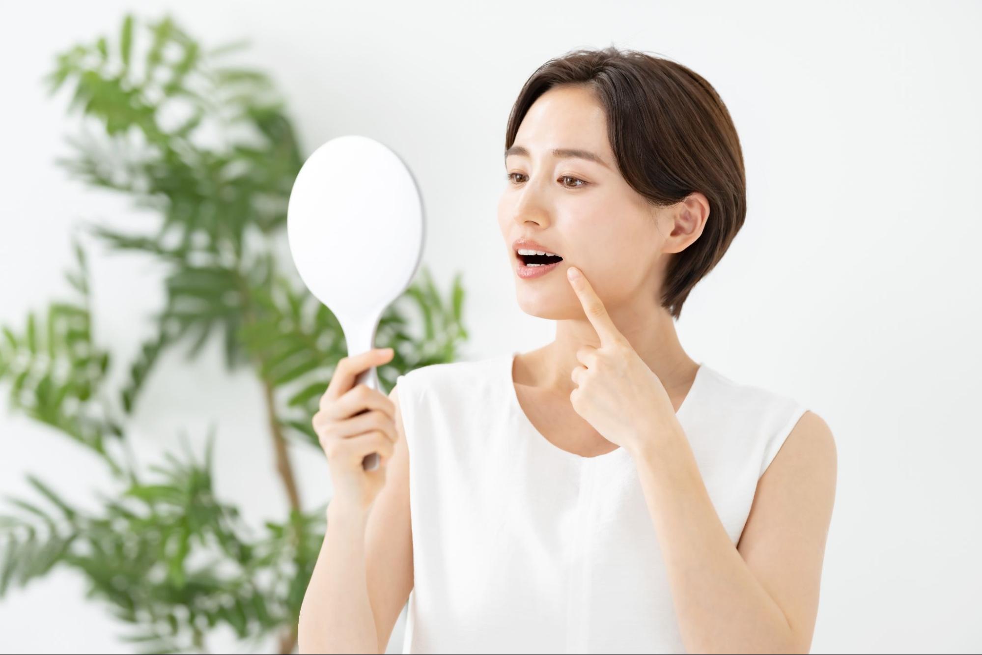 鏡で歯を見る女性