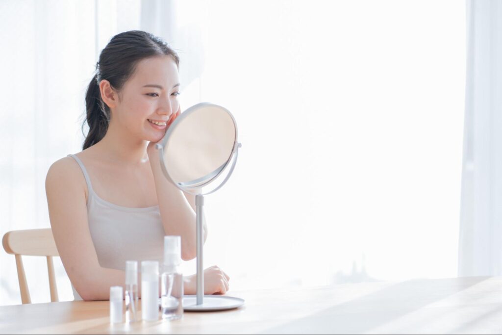 鏡を見ながらスキンケアをする女性