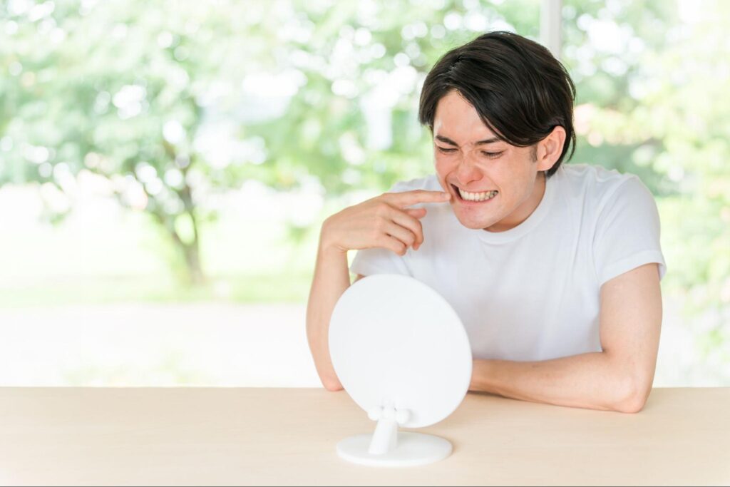 鏡で歯を見る男性