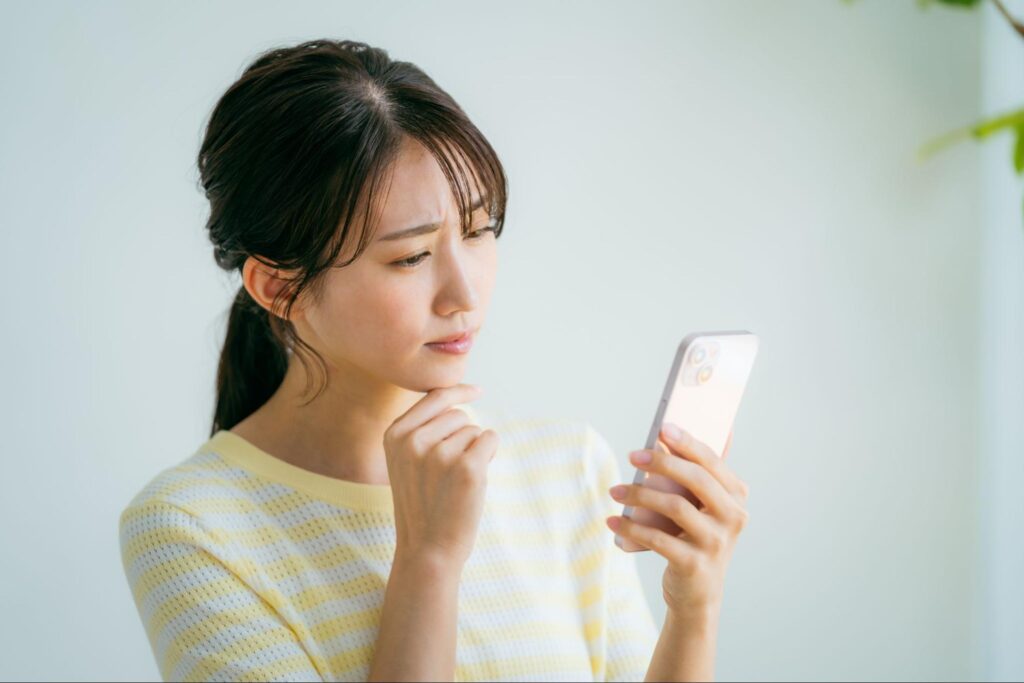 携帯を見ながら悩んでいる女性